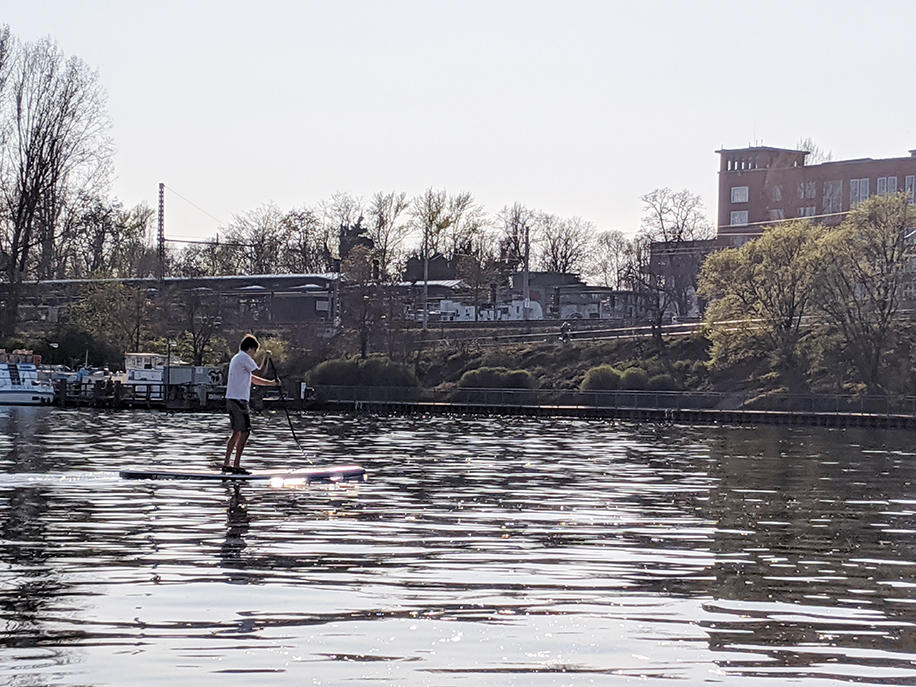 シュプレー川でスタンドアップパドルボートを漕ぐ人